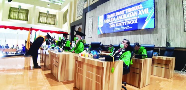 WISUDA - Wakil Rektor I IAIN Bukittinggi, Dr. Asyari, M.Si, memindahkan Jambul seorang wisudawan dalam Rapat Senat Terbuka Wisuda Angkatan ke XVII IAIN Bukittinggi di Student Centre setempat, Kamis(9/12). YURSIL