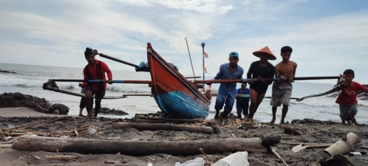 SEMANGAT BANGKIT— Sejumlah nelayan tengah mendorong perahu ke pinggir pantai di kawasan Pantai Padang beberapa waktu yang lalu. Pemulihan Ekonomi Nasional menjadi kejaran pokok pemerintah pada tahun 2022, setelah pandemi Covid-19 terus menujukkan tren yang melandai. IRHAM