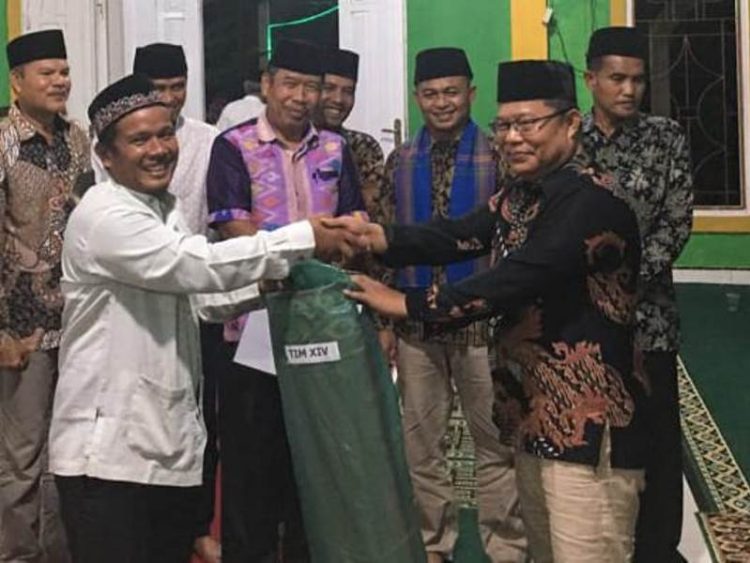 Tokoh masyarakat yang juga anggota DPRD Dharmasraya Fraksi Nasdem, Ampera Labuan Basa menyerahkan tikar untuk Masjid Al Muhajirin dari TSR XIV Pemkab Dharmasraya. MARYADI