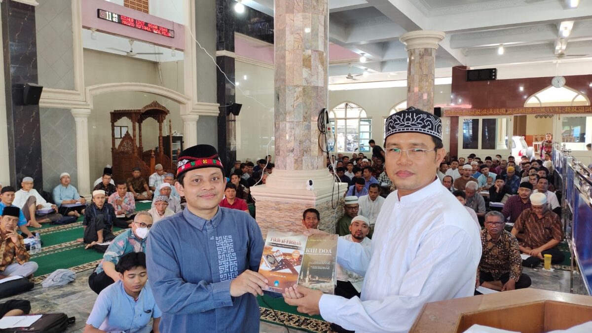 Dr Ahmad Ali (kiri) menyerahkan karyanya kepada Ketua DPW LDII Sumatera Barat H Afrizal Yaman (kanan) di hadapan warga LDII di Masjid Miftahul Huda KPIK Lubuk Minturun Kota Padang, Minggu (6/8). IST