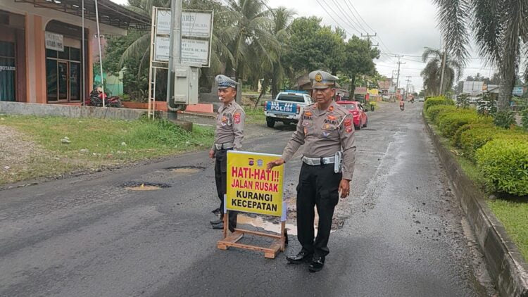JALAN BERLUBANG—Kasat Lantas Polres Agam, Iptu Apriman Sural menunjukan salah satu jalan berlobang di Agam. Satlantas Polres Agam juga memasang rambu tanda bahaya di lubang Jalan Diponegoro, Lubuk Basung itu agar pengguna jalan lebih waspada ketika melewatinya. IST