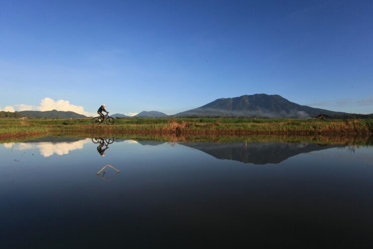 Seorang warga tengah bersepeda berlatar Gunung Marapi di Kota Batusangkar, Kabupaten Tanah Datar beberapa waktu yang lalu. ist/Adi Prima.