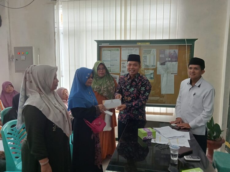 Ketua Baznas Kota Pariaman, Zalman Zaunit menyerahkan bantuan zakat program Pariaman Makmur kepada mustahik yang merupakan pelaku usaha, Senin (18/12). IST