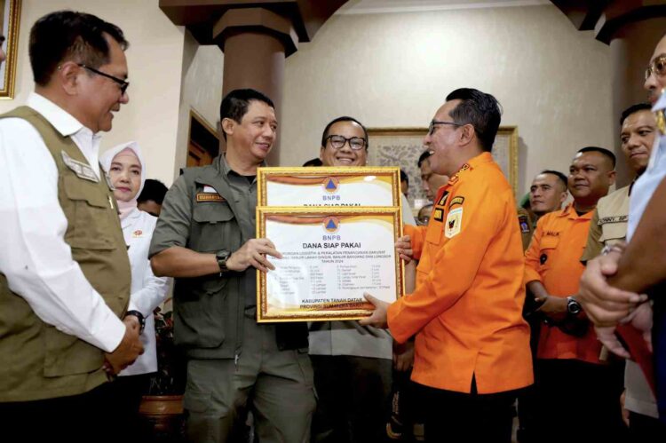 Kepala BNPB Letjen TNI Suharyanto, S.Sos., M.M (kemeja dan rompi hijau), bersama Kepala BMKG Dwikorita Karnawati dan Perwakilan Komisi VIII DPR RI John Kenedy Azis saat memberikan simbolis dukungan bantuan penanganan darurat kepada pemerintah daerah, pada Rapat Koordinasi Penanganan Darurat Bencana Banjir dan Tanah Longsor di Provinsi Sumatera Barat, pada Senin (13/5).