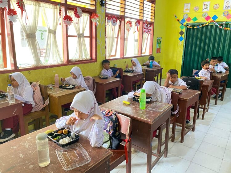 Para siswa SDN 17 Kampung Baru, Kota Pariaman tengah menikmati makan bergizi gratis, Senin (6/1). Meski ditunda di sebagian besar daerah di Sumbar, Kota Pariaman telah memulai program itu pada hari pertama, meski belum menyasar seluruh sekolah. MITHA