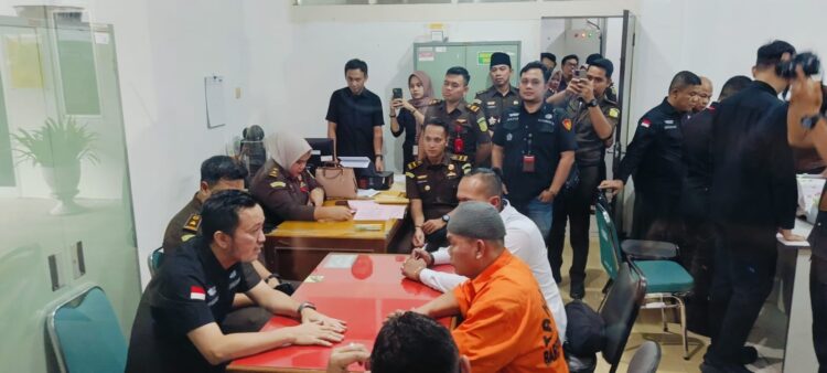Tersangka DI, yang memakai baju orange saat menjalani tahap 2 di Kejari Padang, Rabu (19/3). WINDA
