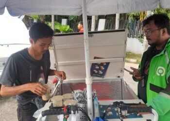 Bima, seorang penjajal kopi gerobak tengah melayani pembeli. KIKI NOFRIJUM