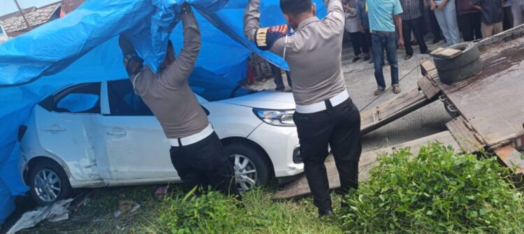 Petugas kepolisian menutup mobil yang ditabrak kereta api dengan terpal di Jati Parak Salai, Kamis (21/8)