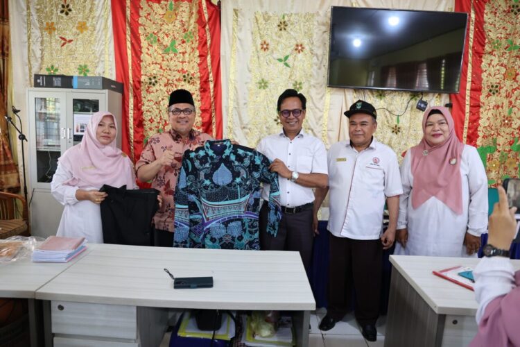 Ketua DPRD Sumbar, Muhidi  menyerahkan bantuan baju batik untuk guru sekolah yang ada ada di Padang. IST