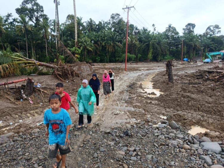 Warga Palembayan, Agam, di antara bekas banjir dan longsor yang melanda mereka, difoto Rabu (10/12). BNPB